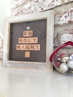 a christmas tree made out of scrabbles in a frame next to ornaments