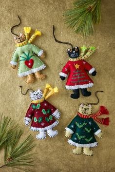 three christmas ornaments hanging from a pine branch on a table with other decorations in the shape of teddy bears