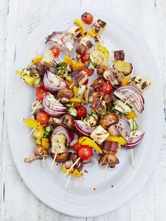 a white plate topped with meat and veggies on skewered toothpicks