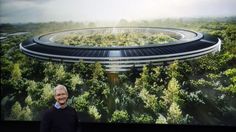 an older man standing in front of a large screen with a futuristic building on it