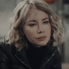 a close up of a person wearing a black jacket and looking at the camera with an intense look on her face