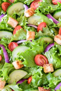 a salad with cucumbers, tomatoes and croutons in a white bowl