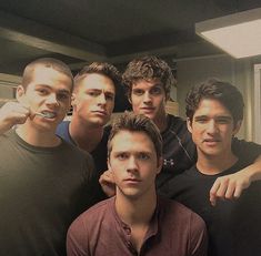 four men are posing for the camera with one man brushing his teeth in front of them