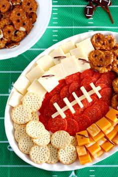 a football shaped cheese board with crackers, pretzels, and meats