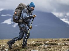 a man with a backpack and poles walking up a hill