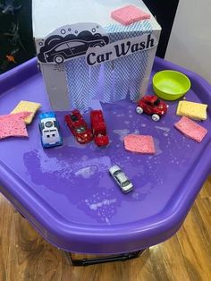 a toy car wash station with cars and sponges on the table, next to it's box