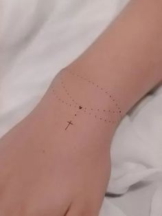 a person's hand with a cross tattoo on it and dots all over the wrist