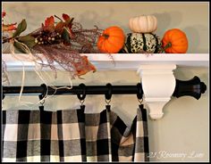 some pumpkins and gourds are sitting on a shelf above the window sill