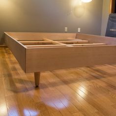 a wooden bed frame sitting on top of a hard wood floor in an empty room