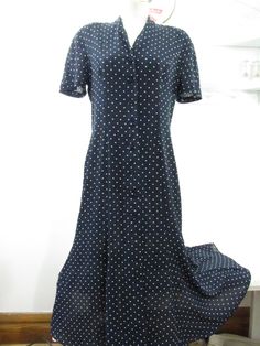 Navy blue shirtwaist dress with a button down front. Easy to wear style can be worn as a duster since it unbuttons all the way down Condition: Good. Fabric is all intact with no fading or scratching of the printed-on design. Seams and hem intact. 100% Polyester with good drape. Rough but not scratchy. Easy care, very washable and quick dry. Slip underneath recommended due to the type of fabric it is Size: 12 Bust: 20" across Length 51" ♥ All measurements are taken in inches. Please ensure fit be Casual Semi-formal Short Sleeve Shirt Dress, Formal Short Sleeve Shirt Dress With Button Cuffs, Polka Dot Button-up Dress, Polka Dot Button-up Dress With Buttons, Polka Dot Short Sleeve Formal Dress, Formal Short Sleeve Polka Dot Dress, Polka Dot Collared Dress With Buttons, Casual Polka Dot Button-up Dress, Collared Polka Dot Dresses With Buttons