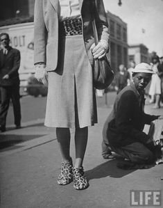 an old black and white photo of a woman standing on the street