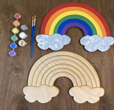 a wooden cutout with paint, paints and rainbows on the table next to it