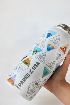 a hand holding a water bottle with stickers on it