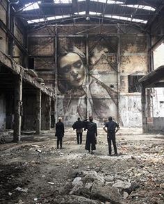 three men are standing in an abandoned building