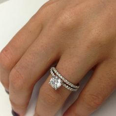 a woman's hand with two diamond rings on her left and the other hand holding an engagement ring