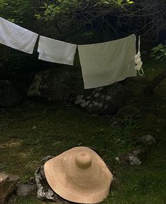 a hat is sitting on the grass next to some clothes hanging from a line outside