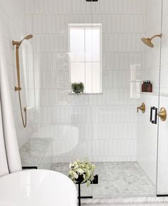 a bathroom with white tile and gold fixtures on the shower head, tub, and sink