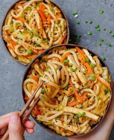 two bowls of noodles with carrots and green onions