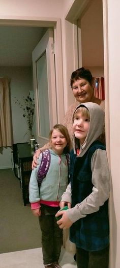 two girls and an adult standing in a hallway