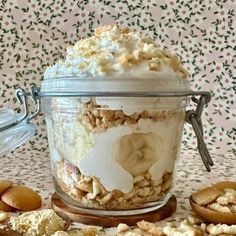 a glass jar filled with food on top of a table next to cookies and spoons