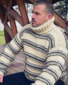 a man sitting on the ground wearing a sweater