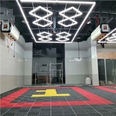 the inside of an empty building with red and yellow floor tiles on the floor, lights hanging from the ceiling