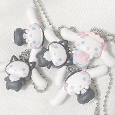 several white and gray items are on a silver chain, with one black cat in the middle