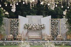 an outdoor ceremony setup with white flowers and greenery on the wall, couches and chairs