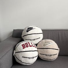 three white and black basketballs sitting on top of a gray couch next to each other