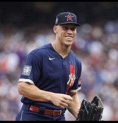 a baseball player holding a catchers mitt in his right hand and smiling at the camera