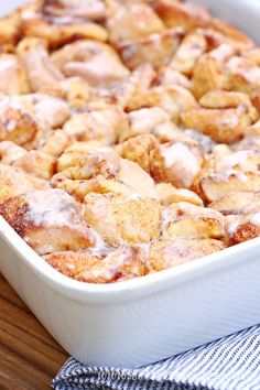 cinnamon rolls in a white baking dish on a wooden table