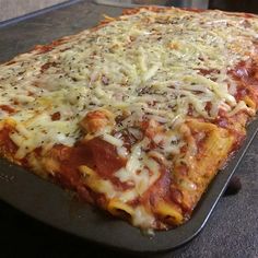 a large square pizza sitting on top of a metal pan covered in cheese and sauce