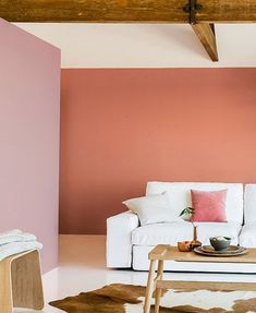 a living room with pink walls, white furniture and cow hide rug on the floor