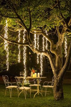 an outdoor table and chairs under a tree with lights