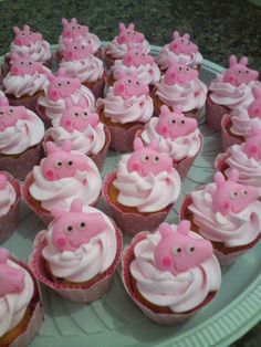 cupcakes with pink frosting and pigs on them are sitting on a plate