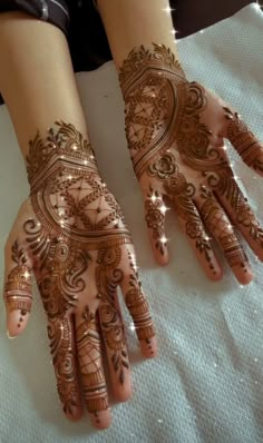 two hands with henna tattoos on them