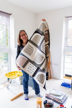 a woman holding up a quilt in her living room