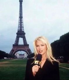 a woman holding a microphone in front of the eiffel tower