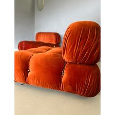 an orange couch sitting on top of a white floor next to a wall mounted mirror