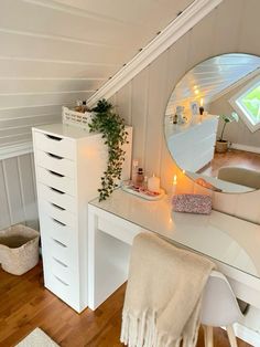 a white vanity with a mirror, stool and plant in the corner next to it