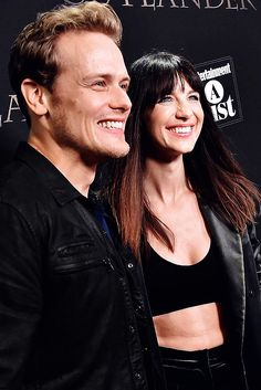 a man and woman standing next to each other on a red carpet at an event