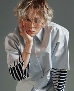 a woman with glasses is leaning on her hand and looking at the camera, while wearing a striped shirt