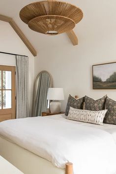 a large bed sitting under a wooden ceiling fan in a bedroom next to a window