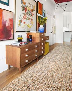 a living room with pictures on the wall and a large rug in front of it