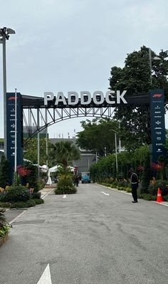 the entrance to paddock in an area with trees and flowers on either side of the road