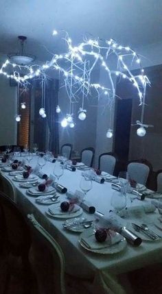 a long table is set with plates and silverware in front of a large chandelier