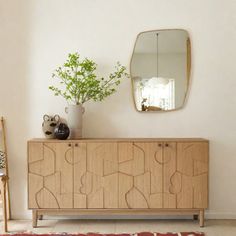 a room with a wooden cabinet, mirror and vase on top of the dresser in front of it