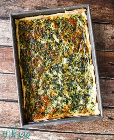 a square casserole dish with spinach and cheese in it on a wooden table