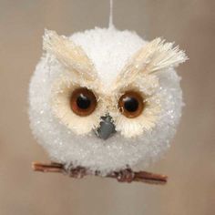 an owl ornament hanging from a branch with snow on it's head