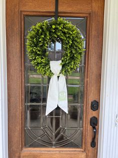 a door with a wreath on it and a white bow hanging from the front door